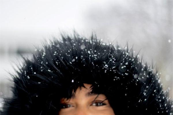  Snowflakes stick to the furry black hood of a college student's coat. 